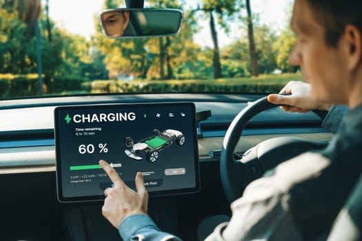 Electric car driver checks battery charging status, range and charging limit on app screen in the car. Smart technology device show EV car recharging data of electric storage in car battery innards.