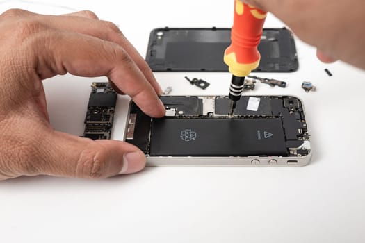 Technician repairing inside the smartphone motherboard with tools for recovery, The man repair by tightening nut from mobile phone with a screwdriver to fix problem