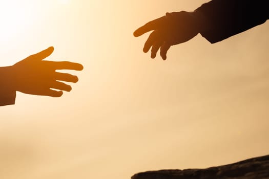 silhouette of hands on the mountain, a man gives a hand to a girl on a mountain, the concept of mutual assistance, motivation for success, place for an inscription. Helping hand. High quality photo