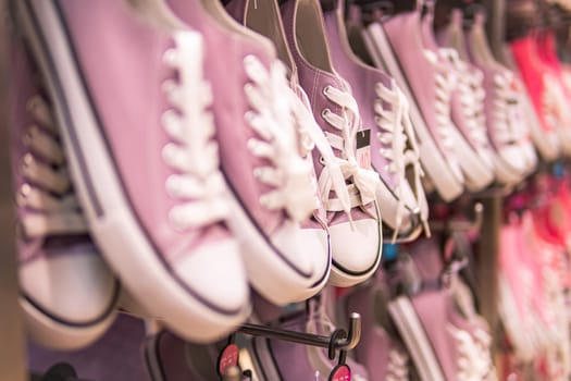 many sports sneakers with pink fabric hanging in the store. High quality photo
