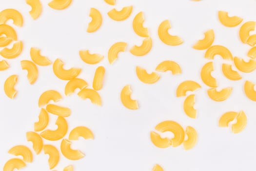 Scattered Uncooked Chifferi Rigati Pasta on White Background. Fat and Unhealthy Food. Classic Dry Macaroni Texture. Italian Culture and Cuisine. Raw Pasta