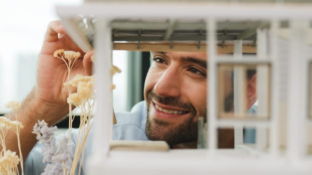 Closeup of young caucasian skilled architect engineer focusing on checking the house model structure with confident. Male worker looking at house construction. Creative design concept. Tracery