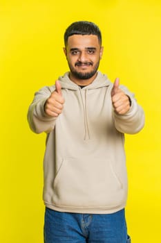 Like. Indian man raises thumbs up agrees with something or gives positive reply recommends advertisement likes good idea feedback, celebrating success victory. Guy on yellow background. Vertical