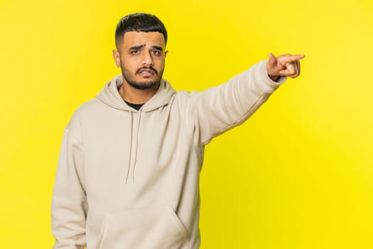 Get out of here. You are fired. Irritated Indian man pointing finger away asking to leave him alone, strict boss firing, conflict, quarrel. Arabian Hindu guy isolated on yellow background indoors