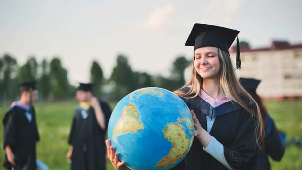 Graduate student girl poses with a globe in a meadow