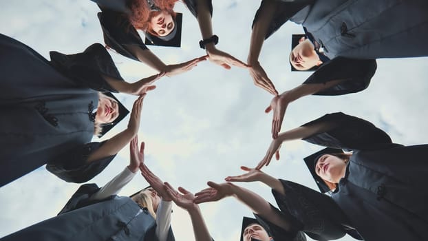 College graduates make a circle of their hands