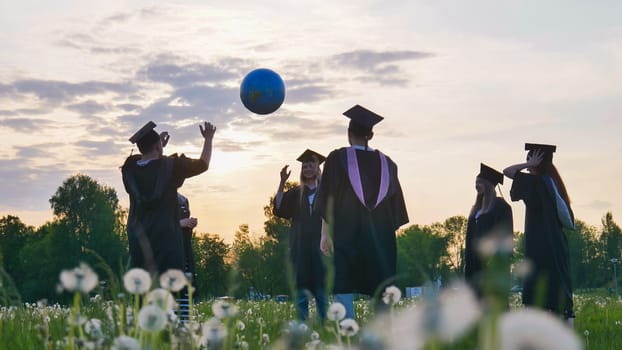 Graduates in costume playing with a ball at sunset