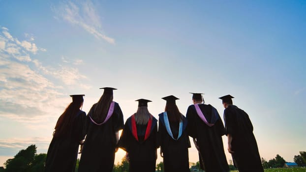 Silhouettes of graduating students at sunset