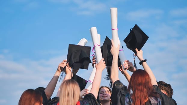 College graduates raise their caps and diplomas upward