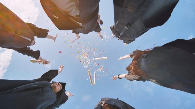 Happy graduates throwing up colorful confetti against the blue summer sky