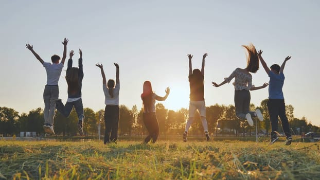 Merry friends jumping around at sunset