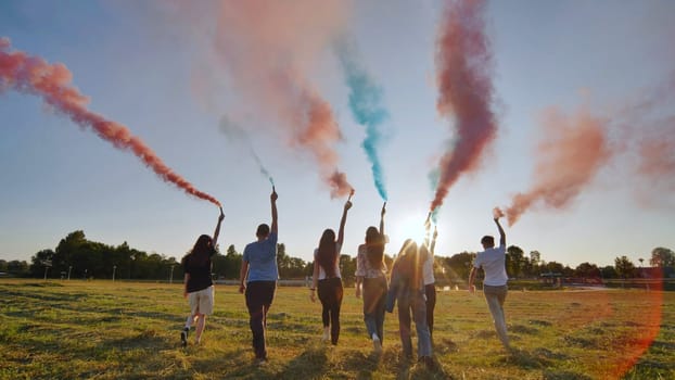 A group of friends spraying multi-colored smoke at sunset