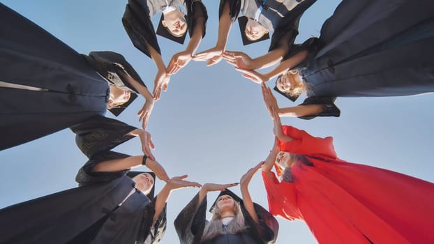 College graduates make a large circle from their hands