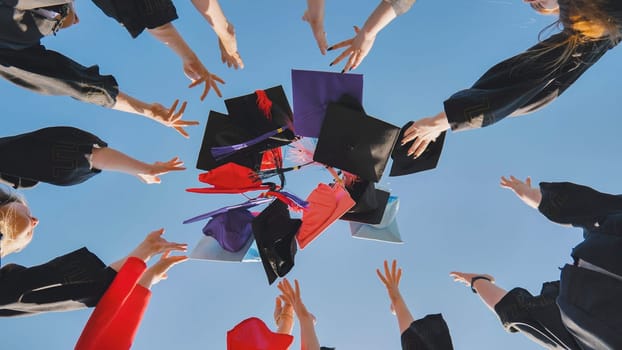 Graduates tossing multicolored hats against a blue sky