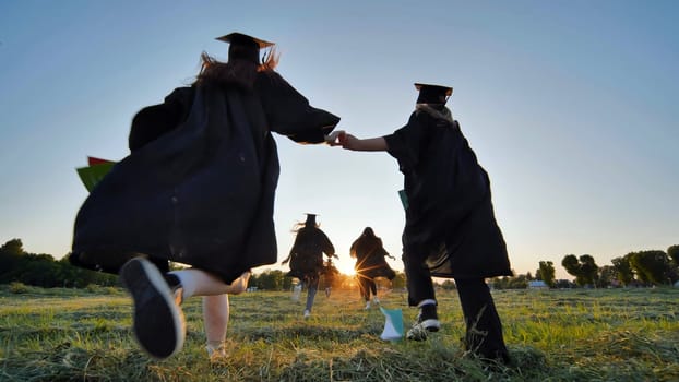 Cheerful graduates students run after school at sunset