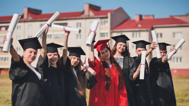 Students graduate holding their diplomas at the top