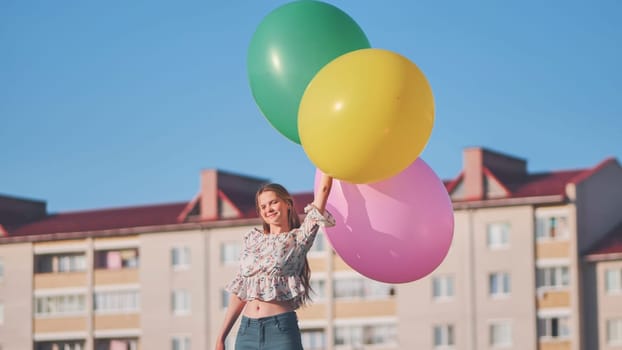 A girl happily poses with large with colorful balloons in the city