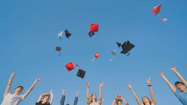 Graduates tossing multicolored hats against a blue sky