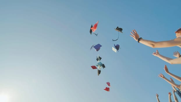 Graduates tossing multicolored hats against a blue sky
