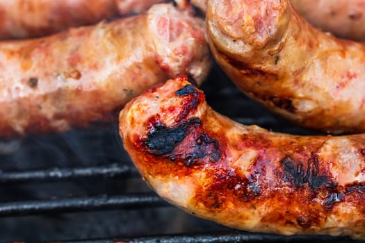 Close up on details of homemade sausages on barbecue grill. Barbecue, grill and food concept.