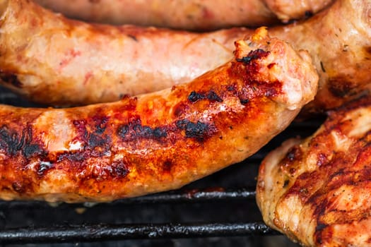 Close up on details of homemade sausages on barbecue grill. Barbecue, grill and food concept.