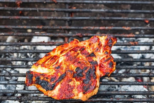 Close up of pork steak grilled on a charcoal barbeque isolated.