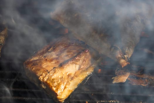 Grilled mackerel fish with smoke on a charcoal barbecue grill.