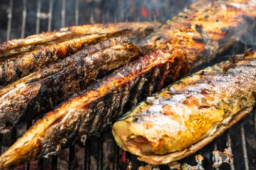 Fish grilled during outdoor party with smoke. Close up fish on the grill