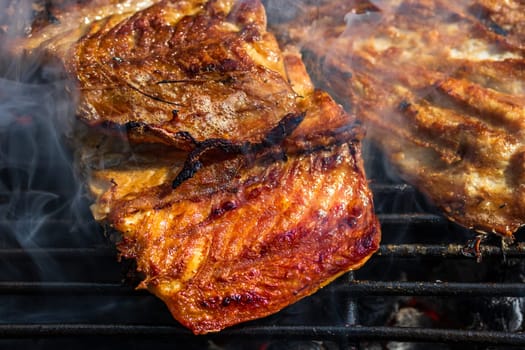 Grilled mackerel fish with smoke on a charcoal barbecue grill.