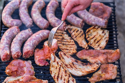 Raw meat on a grill. Sausages and pork meat grilled on a charcoal grill with smoke