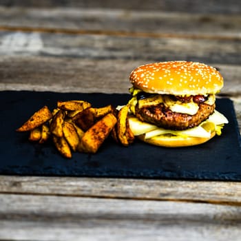 Tasty home made cheeseburger. Cheese burger with pickles, tomatoes, onion, melting cheese