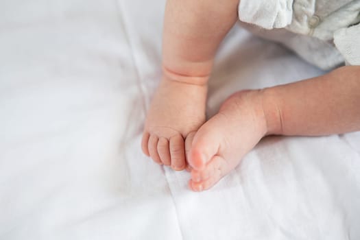 Small feet of a newborn baby on the bed, top view. The concept of motherhood, breastfeeding