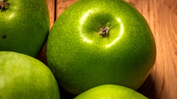 Close up photo of green apples on a wooden board.