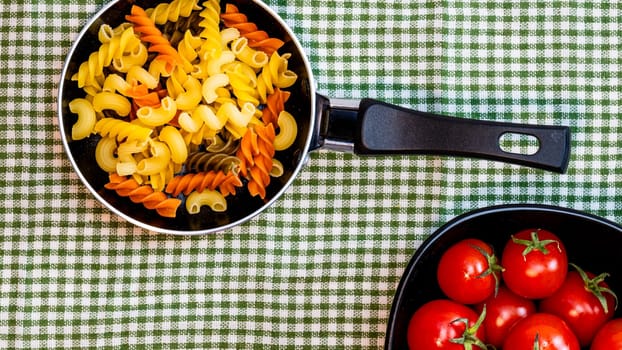 Small mini frying pan with tricolor raw fusilli pasta in a rustic composition.