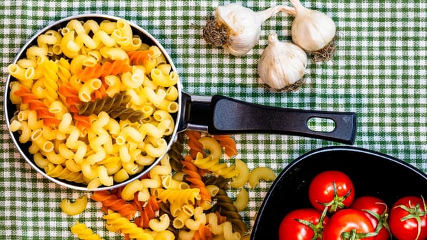 Small mini frying pan with tricolor raw fusilli pasta in a rustic composition.