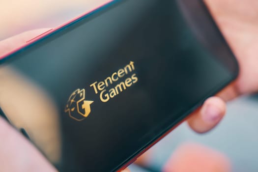 Bishkek, Kyrgyzstan - October 4, 2019: Man holding smartphone with logo of Tencent Games on screen.
