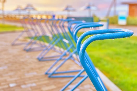 Bicycle Parking empty spaces on the ocean front against sunset and beach umbrellas
