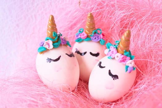 Three Easter eggs unicorns in a pink nest