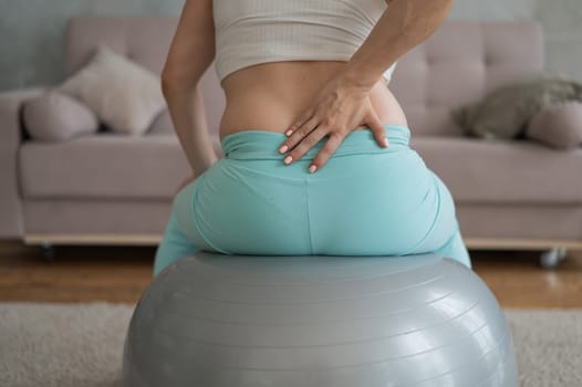 Caucasian pregnant woman suffers from back pain. Fitball training during pregnancy