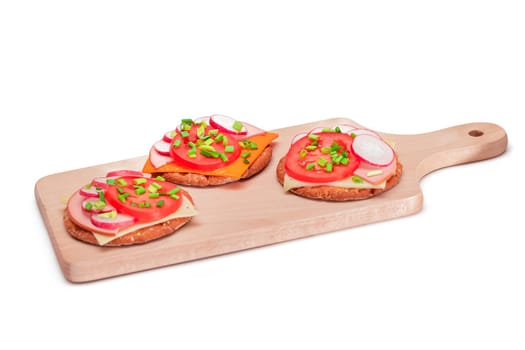 Crispy Cracker Sandwiches with Tomato, Sausage, Cheese, Green Onions and Radish on Cutting Board - Isolated. Easy Breakfast. Quick and Healthy Sandwiches. Crispbread with Tasty Filling - Isolation