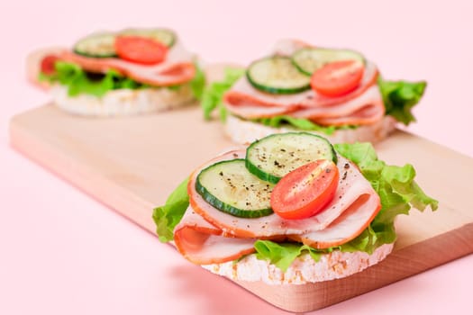 Light Breakfast. Quick and Healthy Sandwiches. Rice Cakes with Ham, Tomato, Fresh Cucumber and Green Salad on Wooden Cutting Board