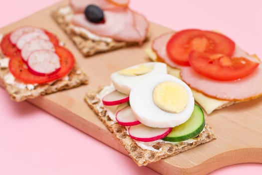 Different Whole Grain Crispbread with Ham, Tomato, Radish, Cucumber and Cheese. Easy Breakfast. Diet Food. Quick and Healthy Sandwiches. Crispbread with Tasty Filling. Healthy Dietary Snack