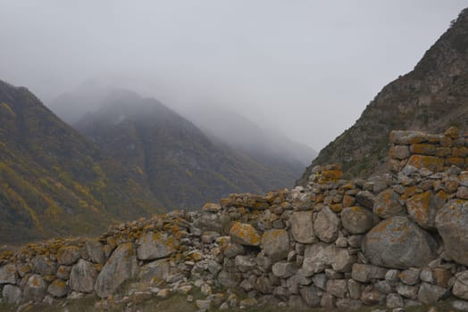 Cloudy foggy sky, mountain peaks covered with fog in the morning. Caucasus Mountains, Upper Balkaria, Russia