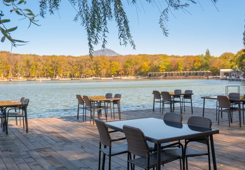 Recreation area in the city park. Outdoor tables and benches by the lake for relaxing and eating.