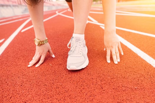 Young, beautiful girl athlete in sportswear is training and running, stretching at the stadium