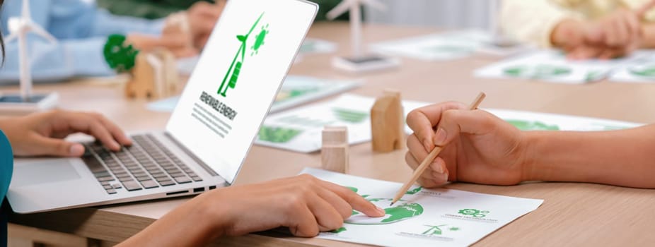 Renewable energy logo displayed on green business laptop while business team represented green design to customer. ESG environment social governance and Eco conservative concept. Closeup. Delineation.