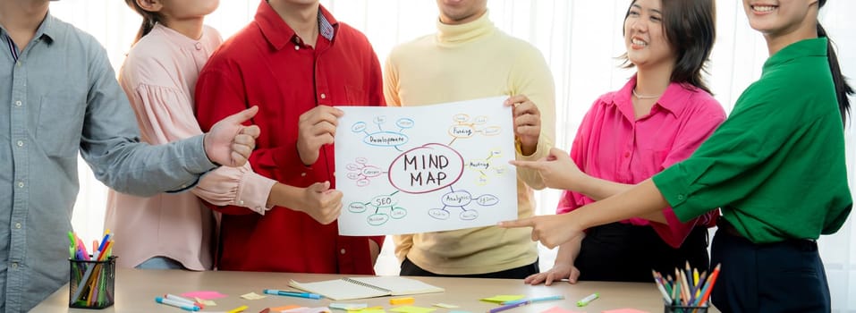 A cropped image of successful businesspeople presents new product marketing strategy using a mind map. Young creative business team brainstorm marketing idea together at modern office. Variegated.