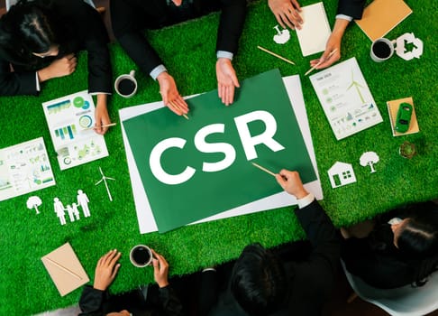 Top view panoramic CSR symbol on green grass table with business people planning for alternative energy utilization for greener sustainable Earth as corporate social responsibility. Quaint