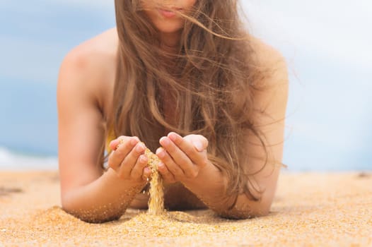 Woman in relaxation on a tropical beach with sand, body parts. sand, time slips through your fingers.