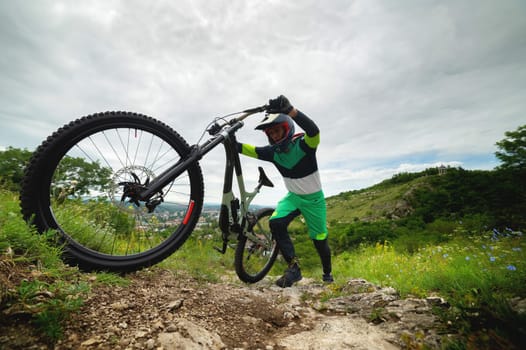 A man pushes a mountain bike up a hill. Adventure travel by bike. Guy athlete in defense lifts his equipment.